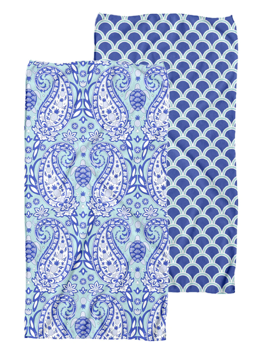 two sided towel. one side is a turquoise base with a navy and white turtle and paisley design. the other side is a navy base with a light blue design 