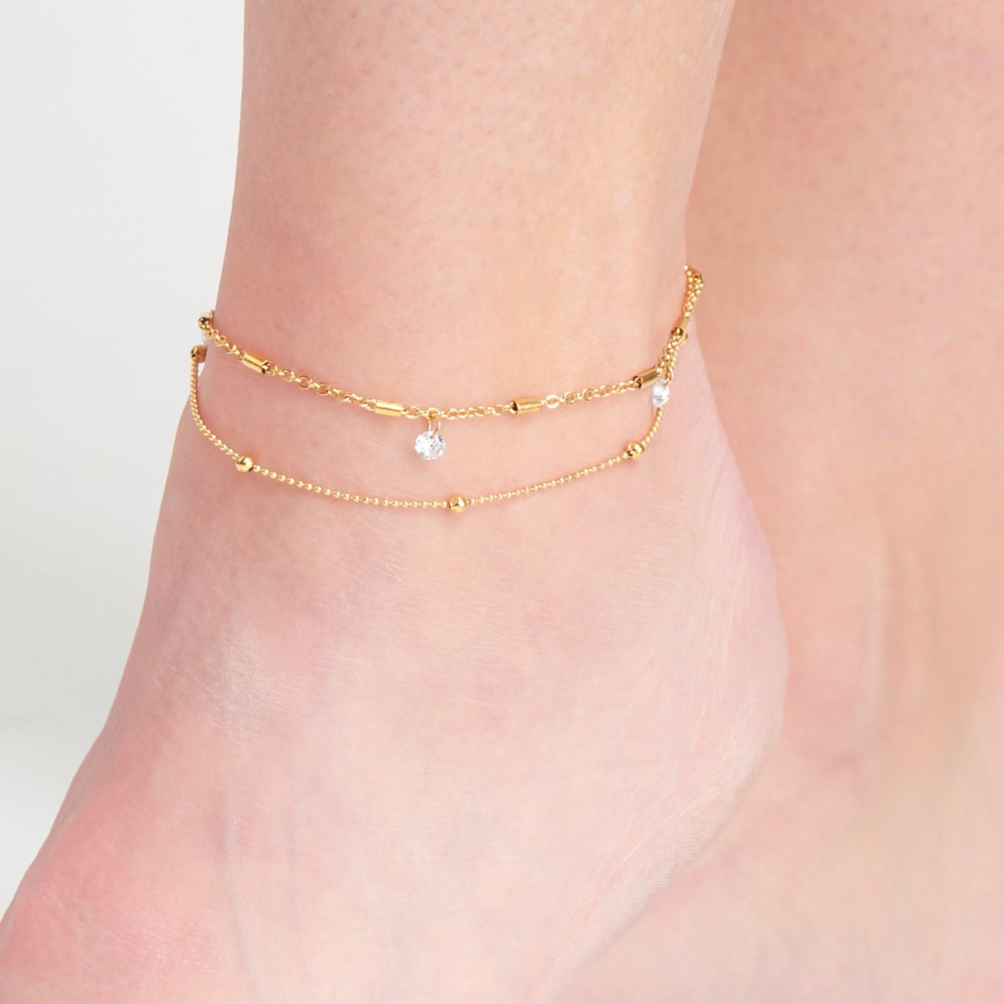gold anklet with two rows, the top one with crystal pendants, and bottom with gold ball detailing