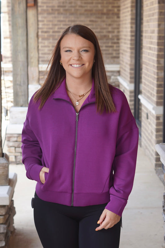 Woman wearing a purple Track Jacket with a Mock Neckline, Long Sleeves, and Side Pockets paired with black leggings