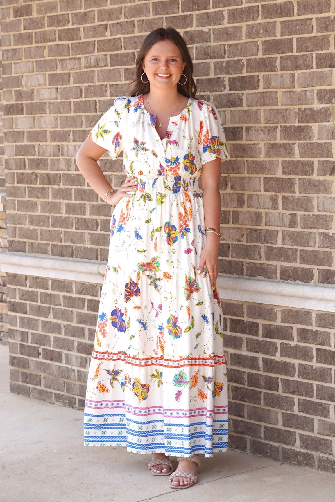 Maxi dress. Cream with multi colored Hawaiian like florals. Short sleeves. V neckline. Cinched waistline underneath the bust. Bottom of the dress is tiered.