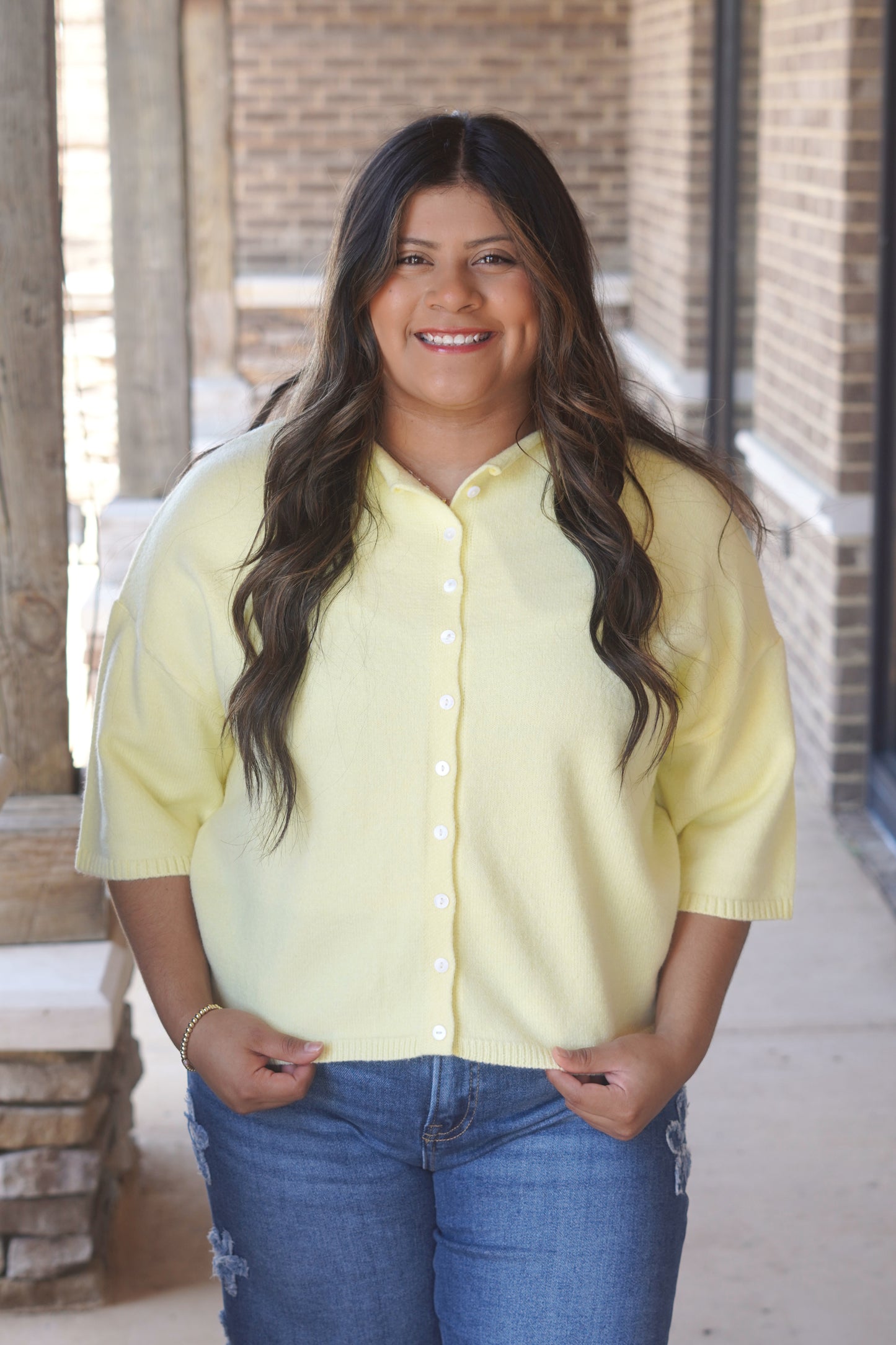Women wearing a yellow short sleeve, button down top.