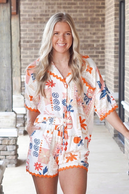 button up top with bright colored floral print, collared neckline, and orange wavy trim