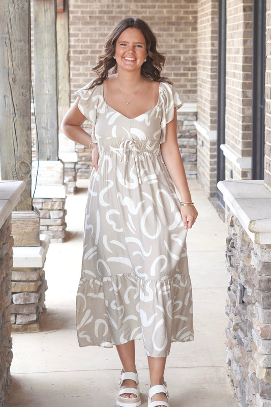 khaki colored midi dress with a white wavy print, cinched tie waist, v-neck, and flutter sleeve