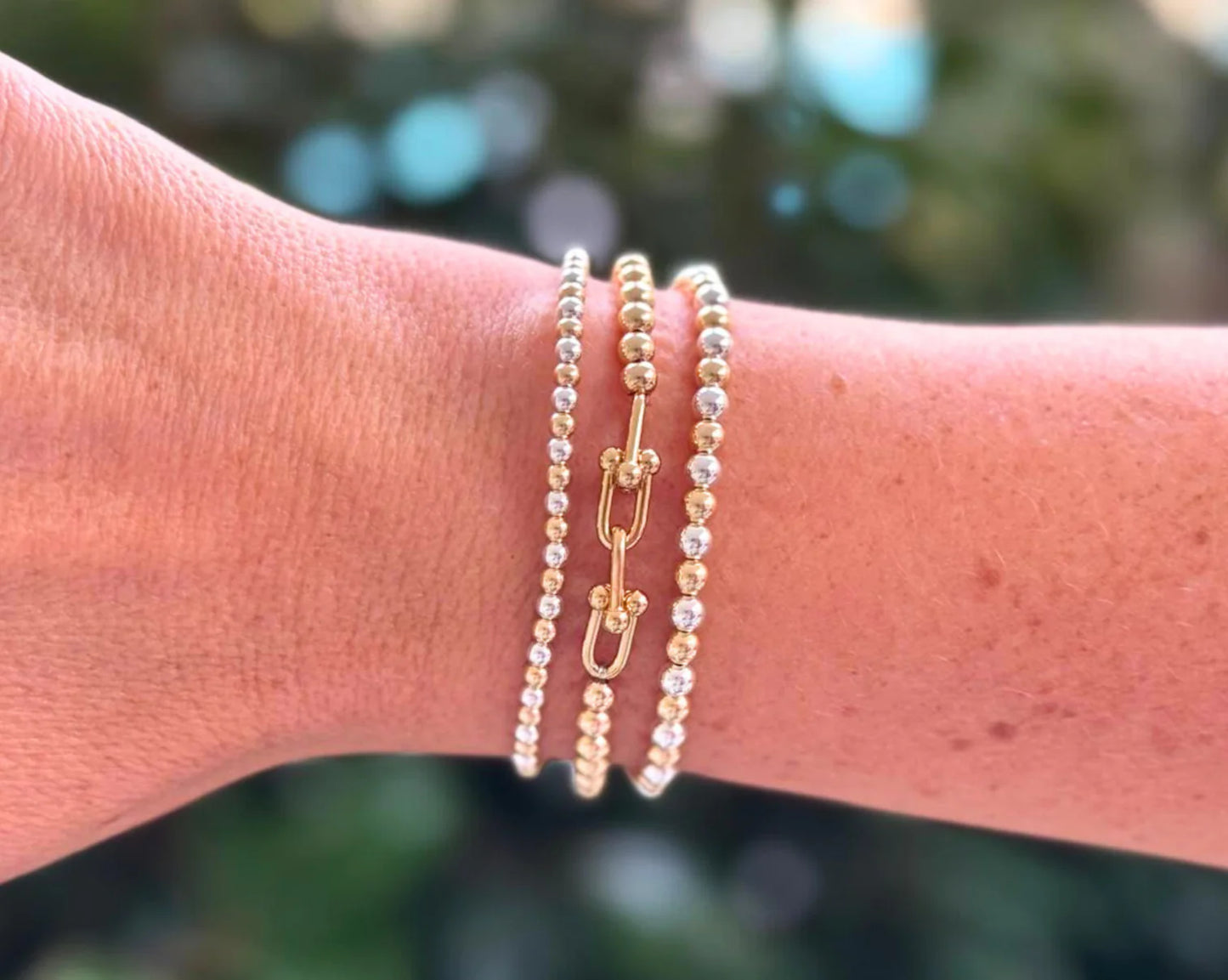 set of 3 beaded bracelets, two of the bracelets being silver and gold alternating, the third bracelet bring gold with a link attaching them