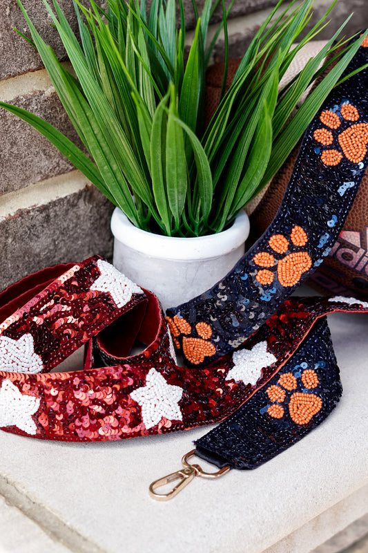 Clear bags can be such a bore when your outfit is on point for game day!! No fear, grab a Game Day Beaded Crossbody Strap whether you are Rolling with the Tide or headed to the Plains!! Sequin Game Day Strap 46.5" including gold hooks. Crimson straps with white stars, and navy beaded strap with orange paw prints.