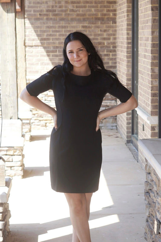 Black dress, fitted short sleeves above the elbow, above the knee, slightly fitted style, round neckline.