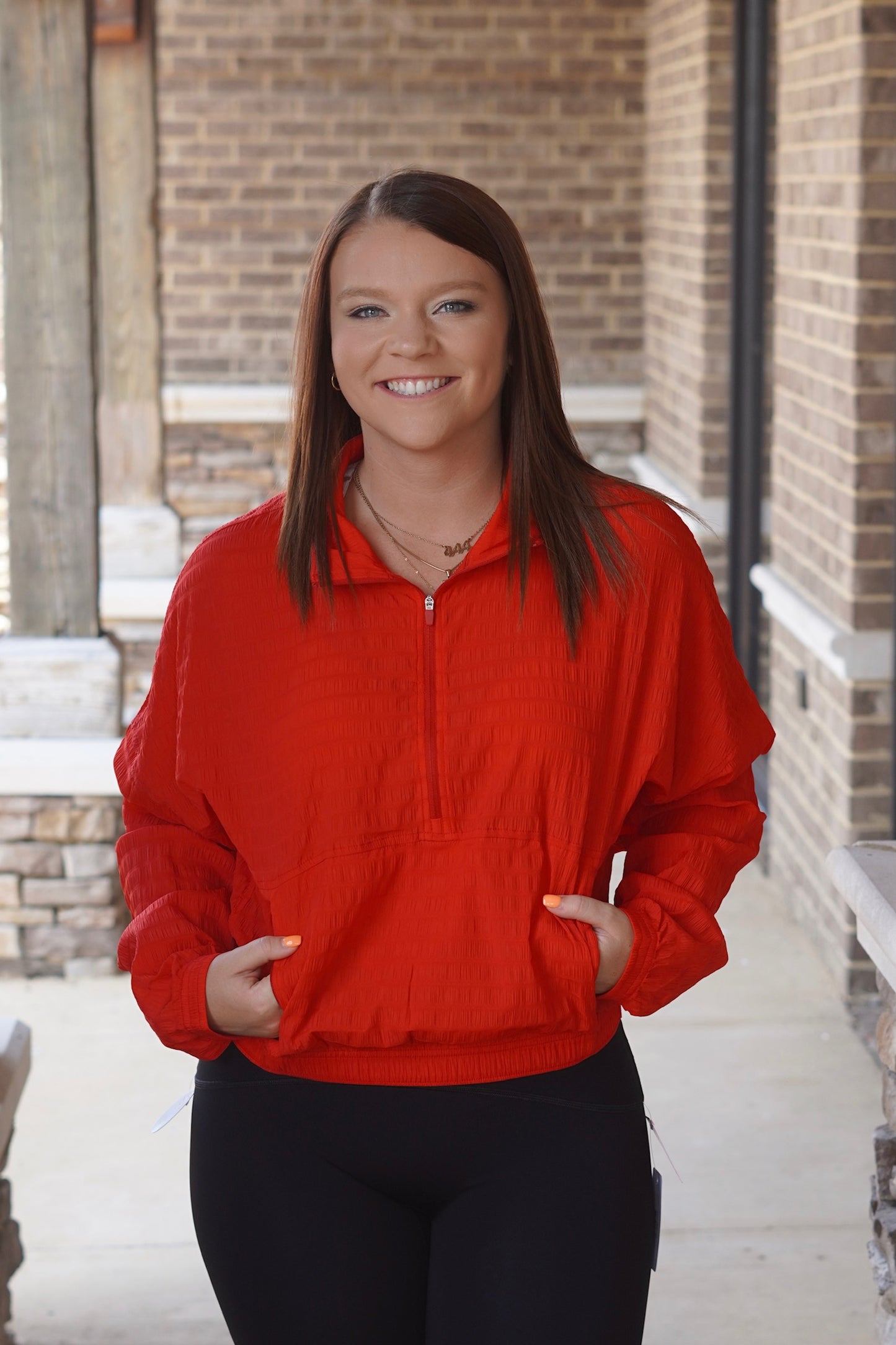 Woman wearing Red Textured Half Zip with front pocket paired with black leggings.