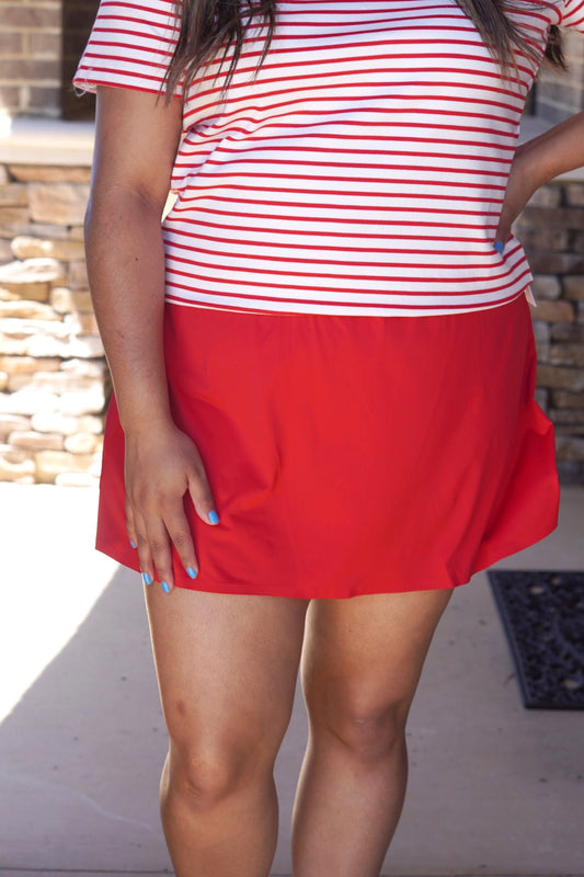 red active skort, flowy fit, elastic waistband, mid-thing length paired with a red and white striped top.