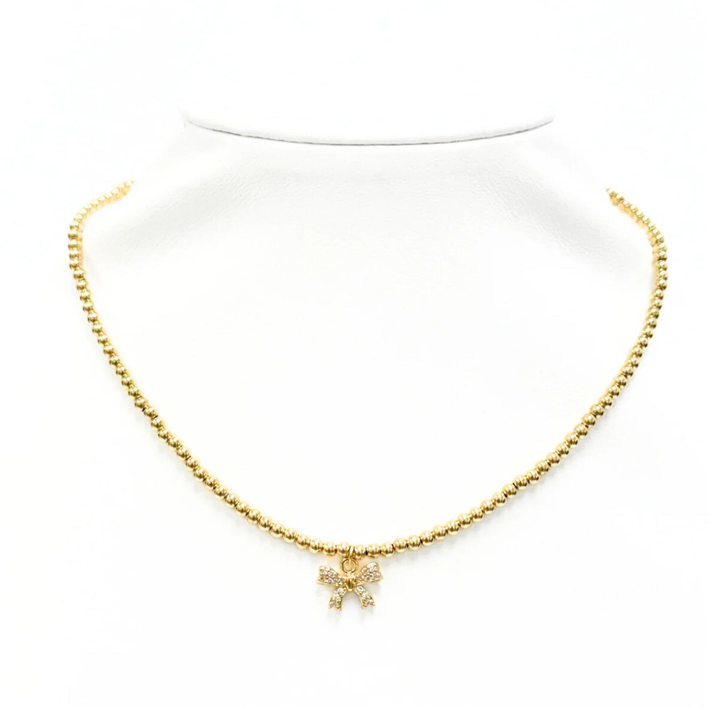 Gold beaded necklace with crystal bow charm