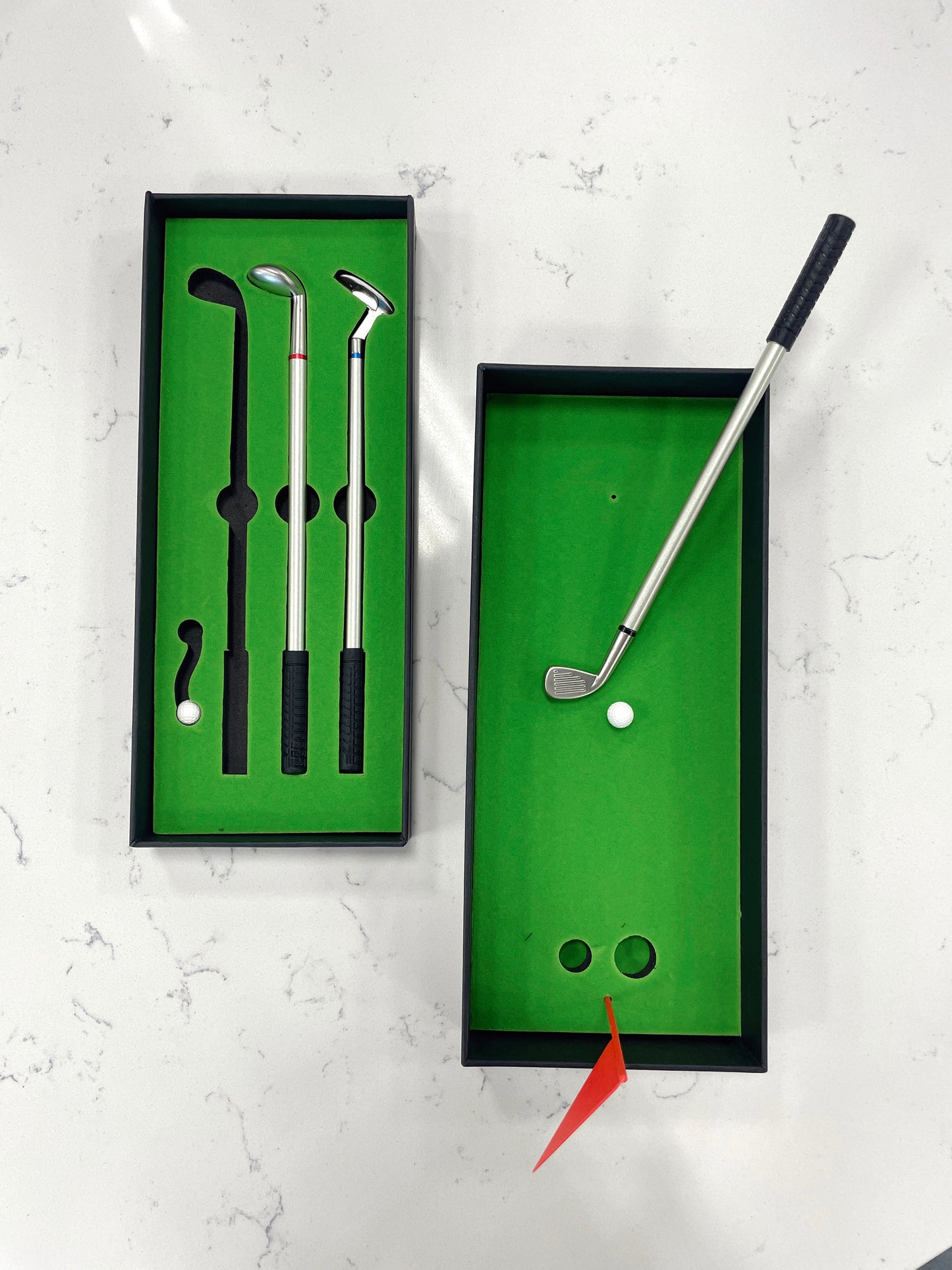 mini gold putting green for desk. 3 golf club pens. two golf balls. red flag