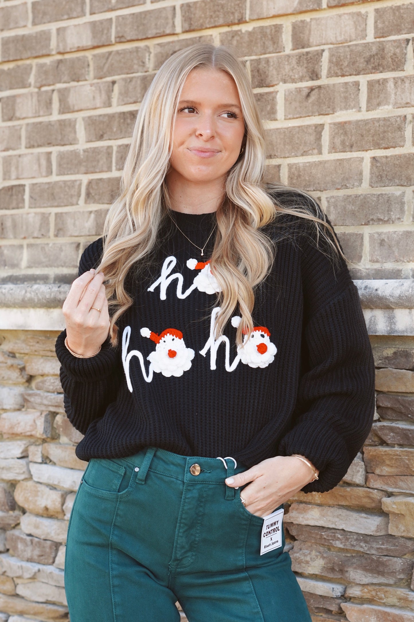 Black knit "ho ho ho" sweater with santa faces as the "O" in "ho"