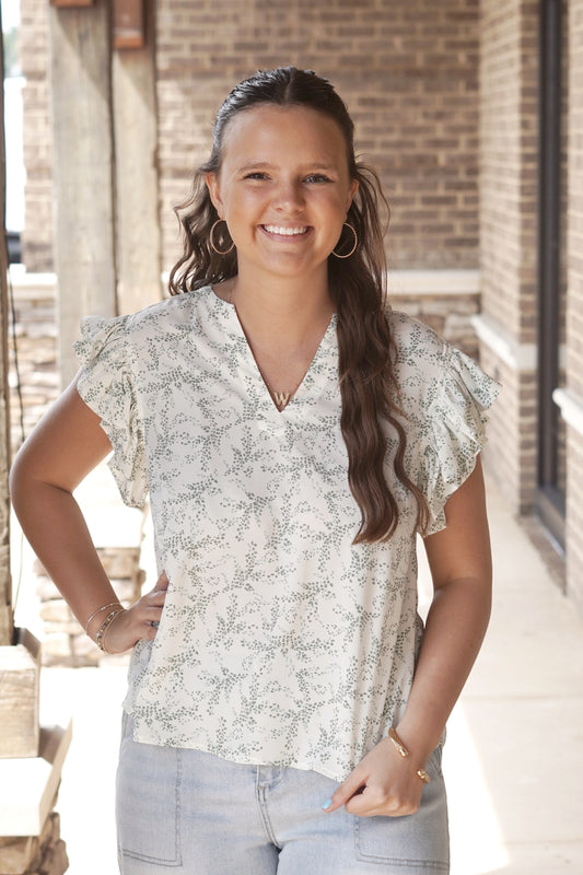 Cream and light green leaf printed top. Ruffled short sleeves. V neckline
