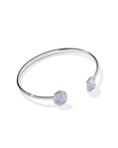 Silver open cuff bracelet with purple stone at the end in a sliver texture frame.