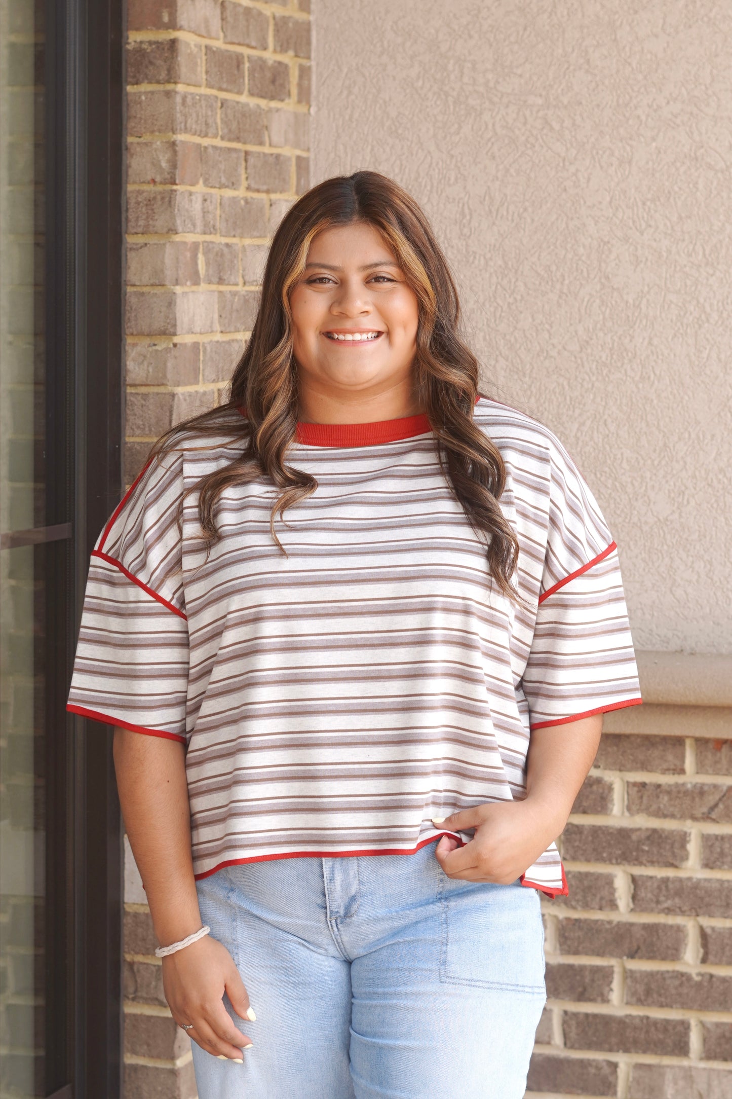 Women wearing short sleeve brown and white striped top, with a red trim.