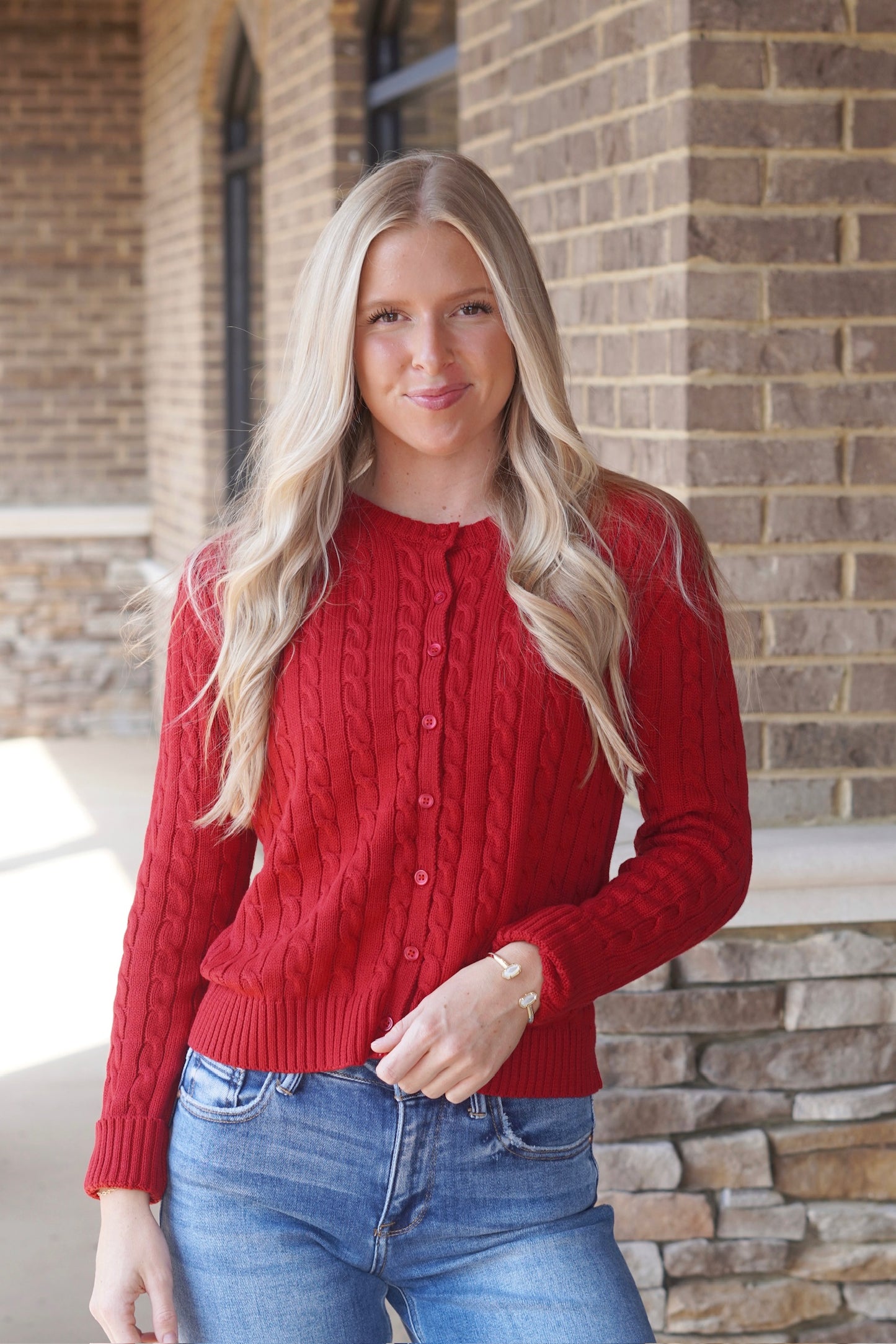 Women wearing a red Cable Knit Cardigan, Round Neckline, Button Up, Long Sleeves, Waistline Length.