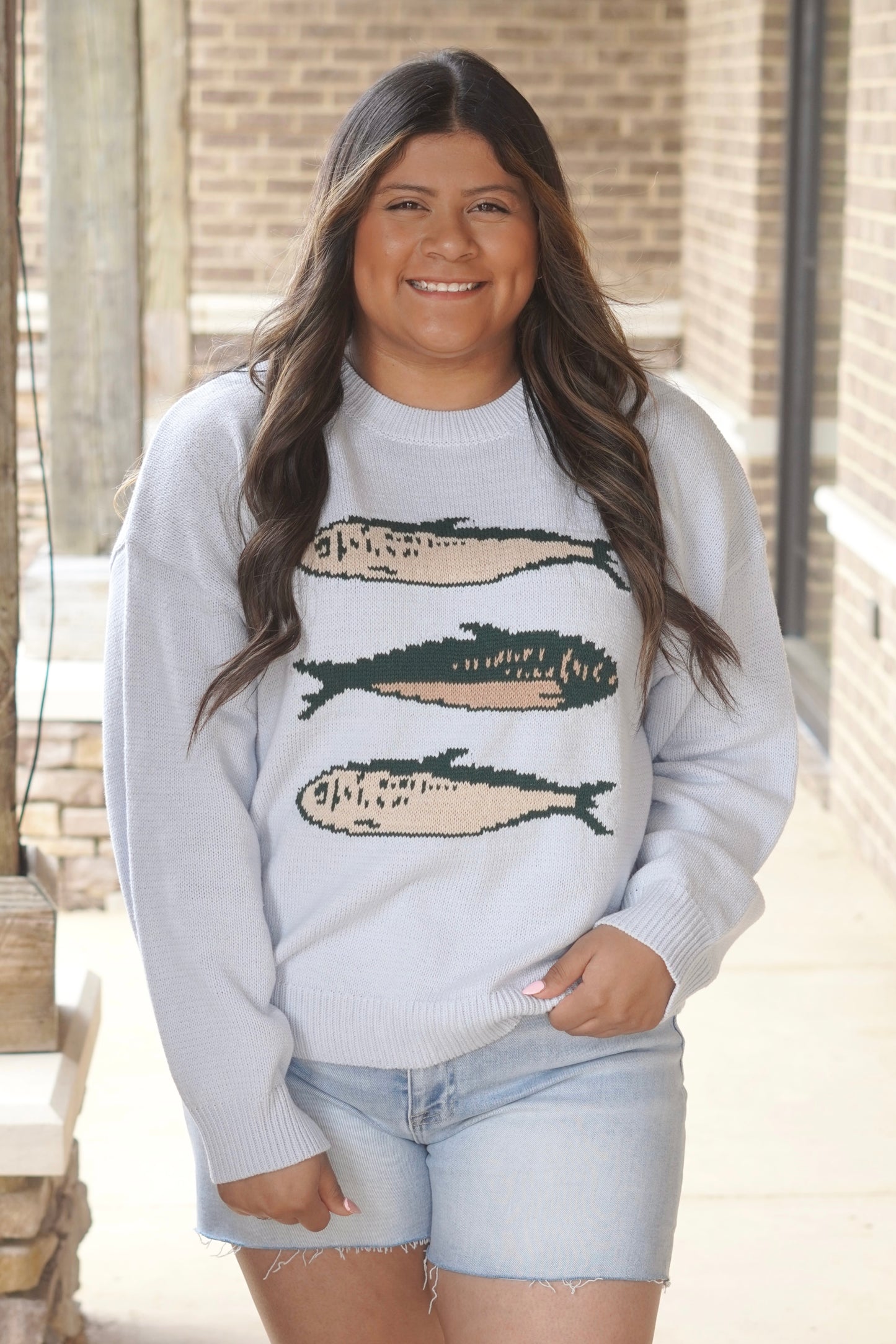 Women Wearing a Baby Blue Sweater with 3 Green Fishes on it.