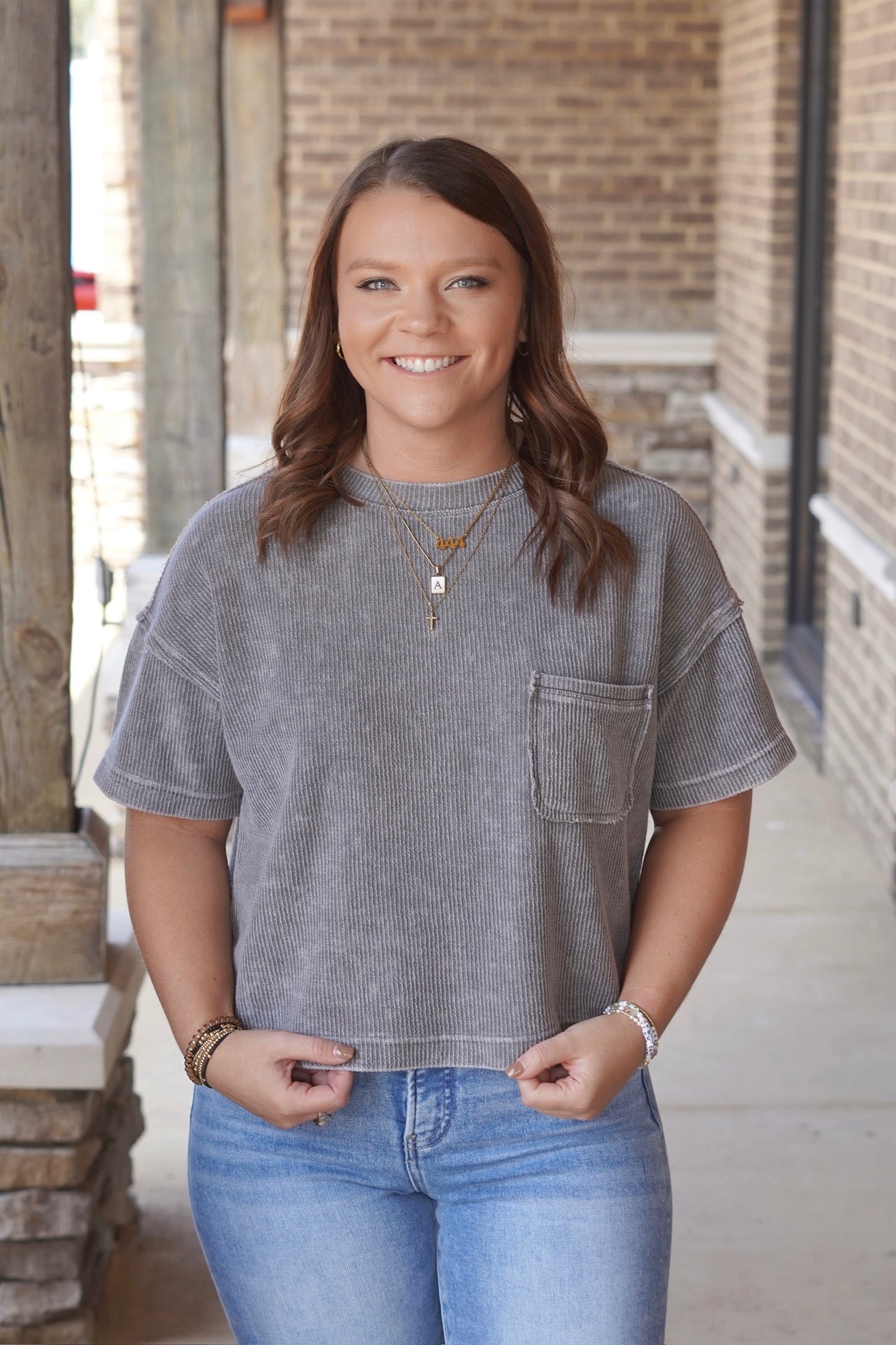 Woman wearing cropped charcoal Ribbed Short Sleeve pocket Tee with a Round Neckline and Short Sleeves paired with jeans