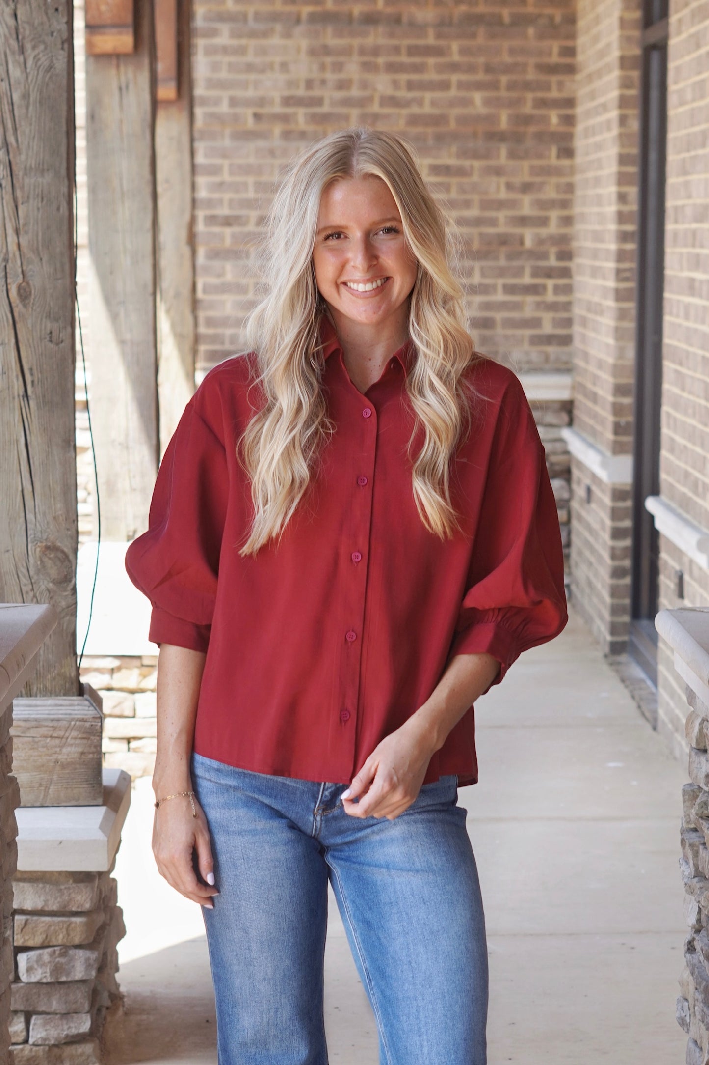 Woman wearing a red short sleeve puff sleeve collared button down shirt paired with denim jeans