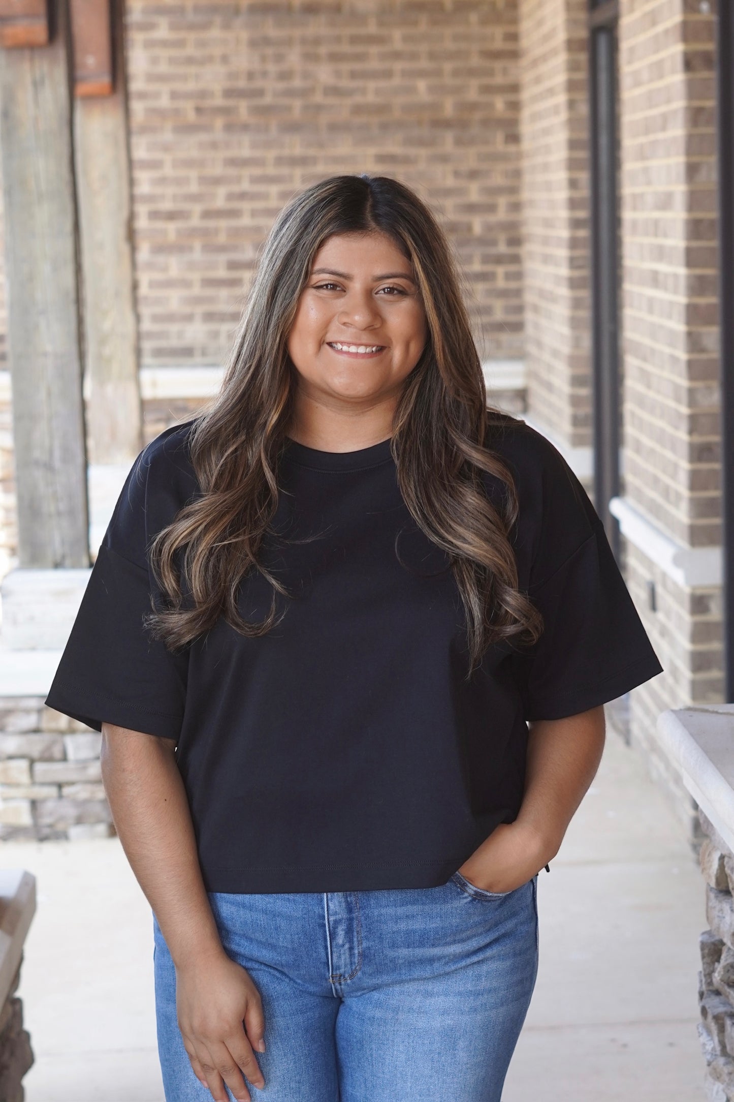Woman wearing a full length black Crop tee with a boxy fit paired with jeans