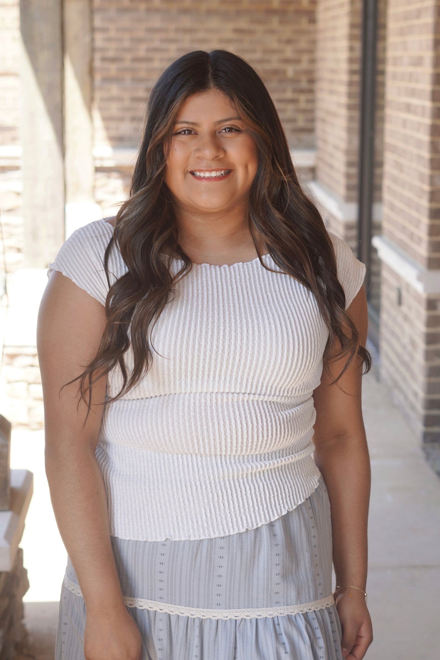 Women wearing a white ribbed top, short sleeve, asymmetrical bottom , fitted, boat neckline.
