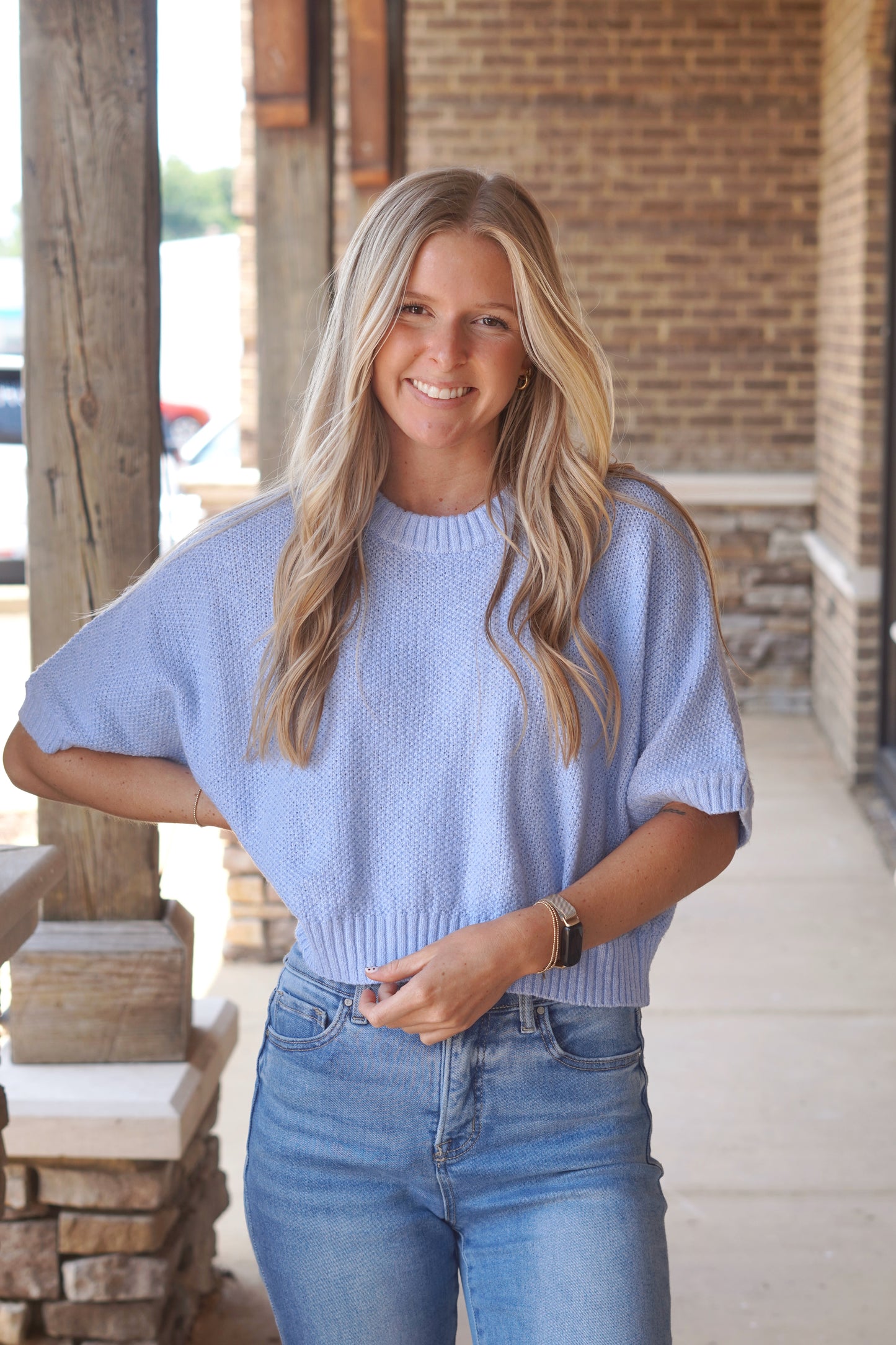 Women wearing a blue top, knit material, short sleeves, crew neckline.