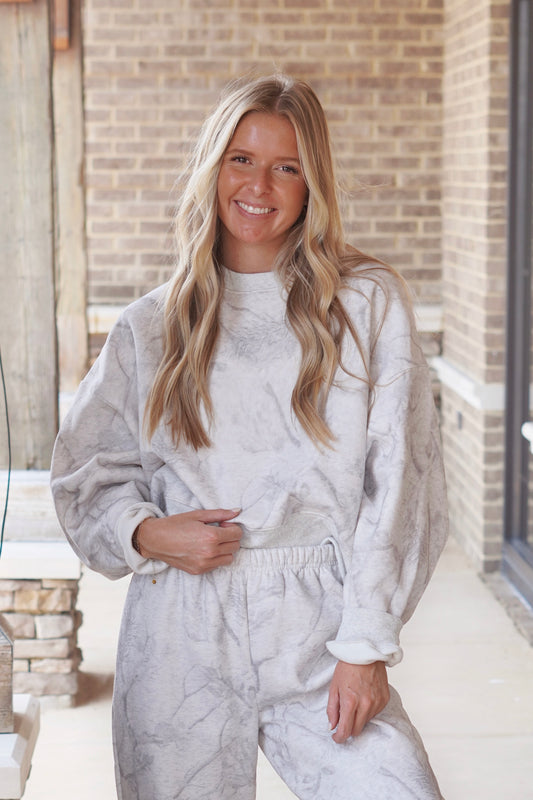 Woman wearing light grey camouflage oversized sweatshirt paired with matching sweatpants