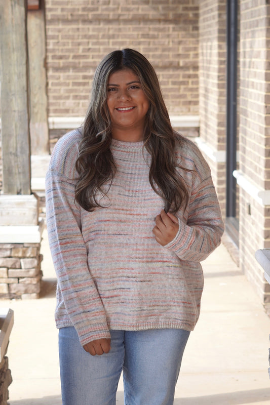 Woman wearing striped multi-color pattern sweater paired with jeans
