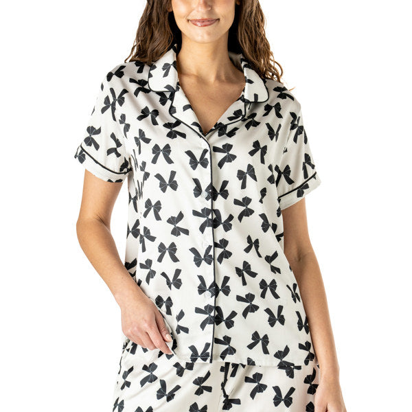 Woman wearing a white and black bow printed button up pajama top with matching pants