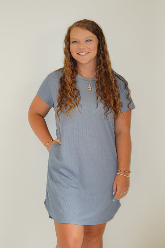 100% Polyester Waffle Knit Mini Dress with pocket detail Round Neckline Short Sleeve Blue color Above the knee length Loose Fit Model is wearing a size medium.