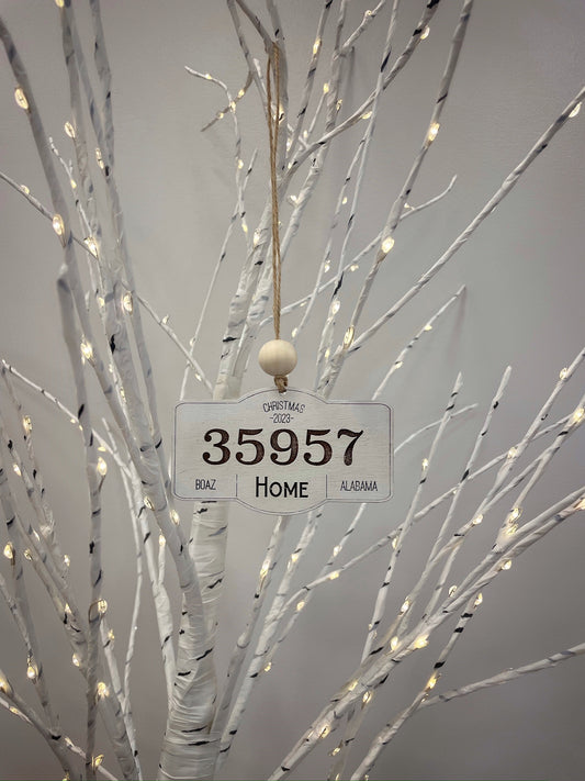 Beige wooden ornament that has 35957 , Boaz, Alabama, and home in all capital letters