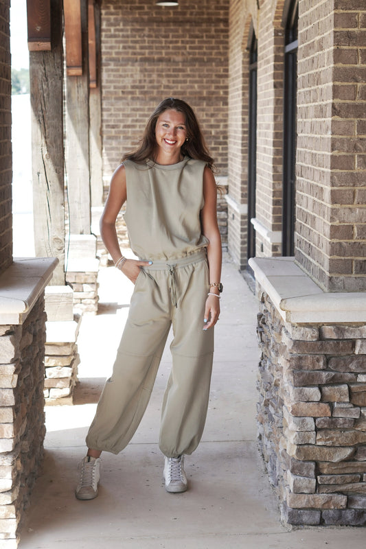 Olive Jogger Pants Jumpsuit Crew Neckline Cap Sleeves Raw Hem Color: Olive Cinched Waist w/ Drawstring Pockets Jogger Pants Full Length Legs 85% Cotton, 15% Polyester