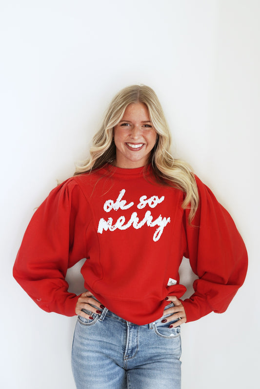 "Oh So Merry" Puff Sleeve Crew Neck Crew Neckline Long Cuffed Sleeves "Oh So Merry" in White Sequin Lettering Color: Red Ribbed Hem Relaxed Fit Full Length 60% Cotton, 40% Polyester