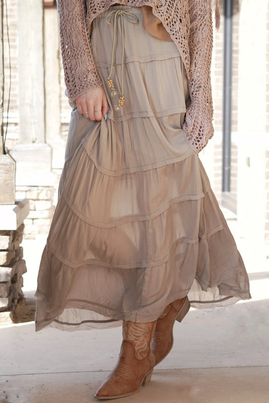 <ul> <li>Traveler Tiered Ruffle Maxi Skirt</li> <li>Elastic Waistband w/ Tie</li> <li>Beaded Tassel on Waist Tie</li> <li>Tiered Ruffle Design</li> <li>Color: Olive Green </li> <li>Silky Gauze Material</li> <li>Relaxed Fit</li> <li>Silky Underlining</li> <li>Maxi Length</li> <li>100% Rayon</li> </ul>