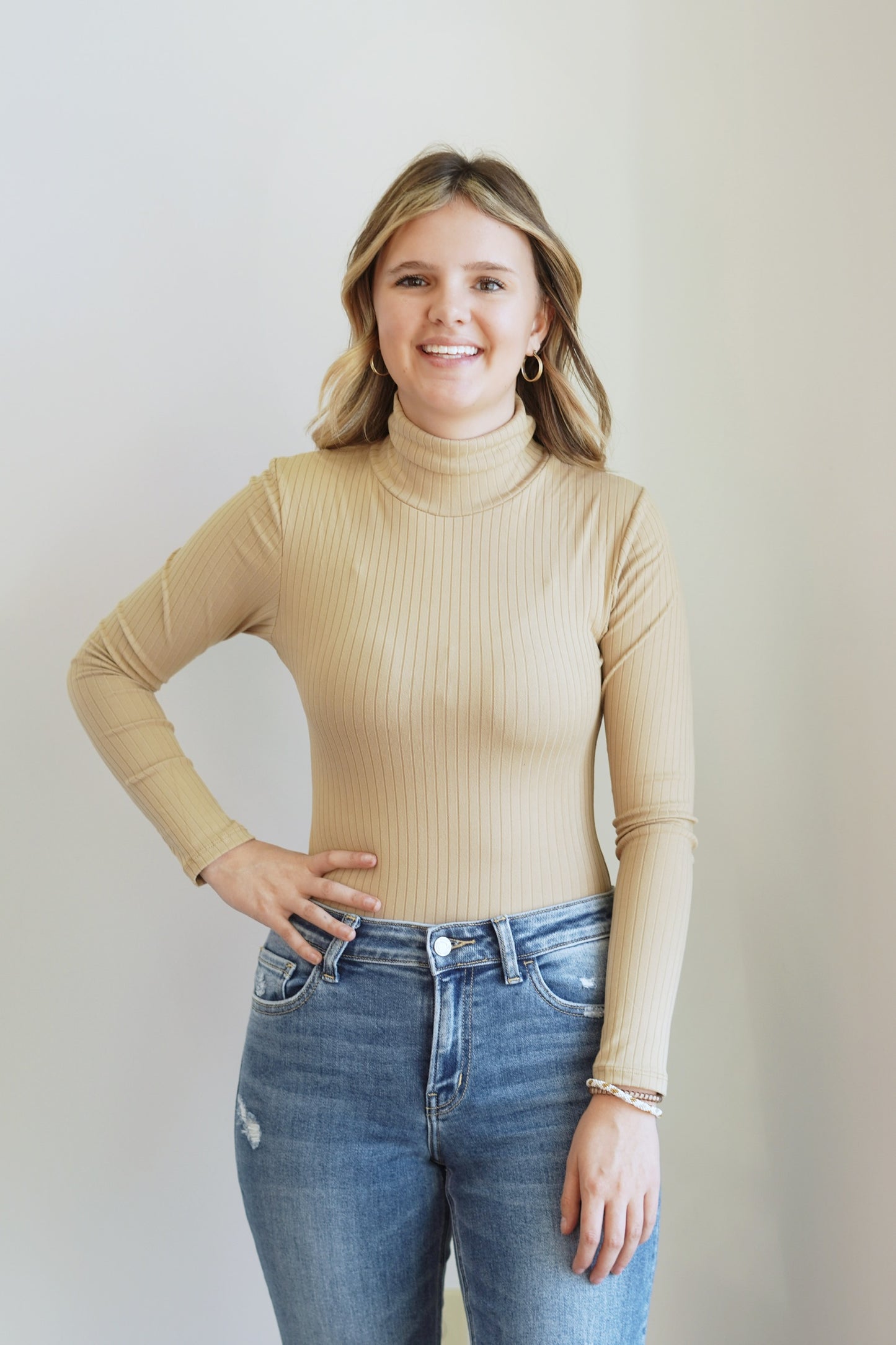 Rory Ribbed Turtleneck Bodysuit Turtleneck Neckline Bodysuit Style Long Sleeves Ribbed Material Button Snap Closure Colors: ,Khaki, 92% Polyester, 8% Spandex