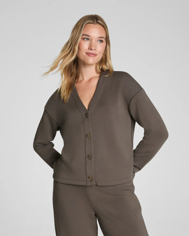 Woman wearing a brown button up cardigan with a V-Neckline and brown pants