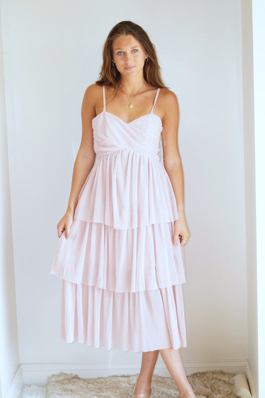 We are in our Enchanted by Taylor Swift era with this beautiful piece! The tulle, the color, and the ruffles make this dress a wonderful addition to your wardrobe. Wear it on a date night, to the beach, or to that wedding you have coming up! You will for sure impress your plus one in this beauty!  Tay Tiered Ruffle Midi Dress Sweetheart Neckline Sleeveless Adjustable Straps  Tiered Ruffle Tulle Material Blush Pink Midi Length ﻿Care: ﻿Hand Wash Cold, No Bleach, Hang to Dry Model is wearing size small