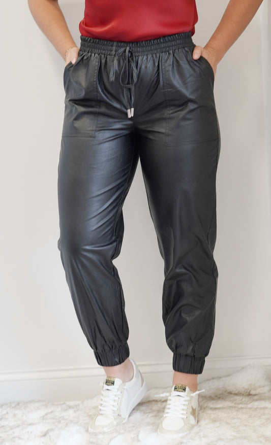 Lola Faux Leather Jogger Pants Smocked Elastic Tie Waistband Jogger Legs Front Pockets Black Faux Leather Jogger Fit 55% Cotton, 45% PU