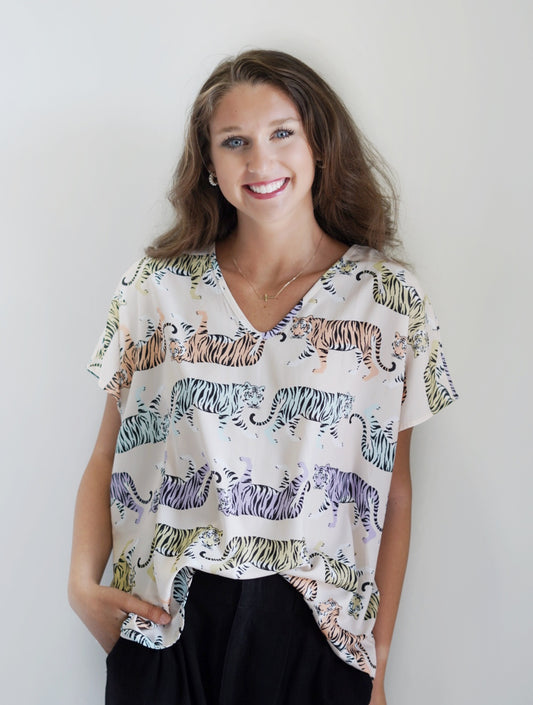 Mae Multicolor Tiger Print Top V- Neckline Cowl Sleeves Multi Color Walking Tigers Print Colors: Beige background; yellow, orange, purple, and blue tigers Full Length Loose Fit 100% Polyester Care: Machine Wash with Like Colors, Tumble Dry Low, Do Not Bleach Model is wearing a size small