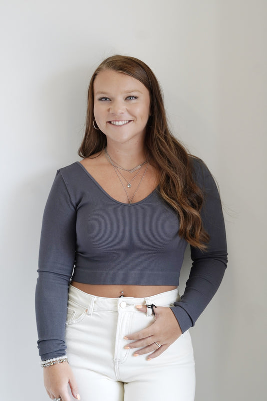 Carolina Cropped Long Sleeve Top Wide V-Neckline Long Sleeves Ribbed Stretchy Material Colors: Slate Grey Cropped Fitted 92% Nylon, 8% Spandex Care: Hand wash cold, Lay flat to dry, Do not iron, Non-Chlorine Bleach