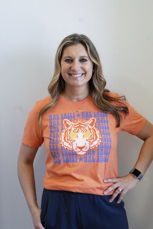 War Eagle Tiger Graphic Tee Crew Neckline Short Sleeves Orange Base Navy "War Eagle" Lettering Tiger w/ Star Eyes Graphic Full Length Relaxed Fit 60% Cotton, 40% Polyester