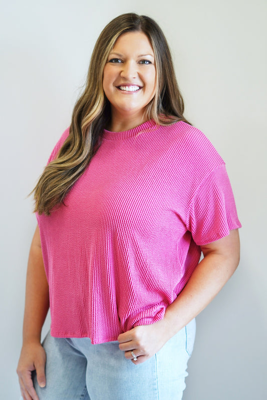 Mia Relaxed Lush Rib Top Round Neck Short Sleeves Color: Fuchsia 76% Polyester, 21% Rayon, 3% Spandex Hand Was Cold, Do not Bleach, Hand Or Line Dry Model is wearing size 1XL