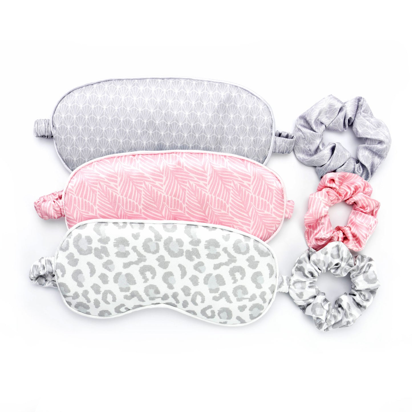 Multi-colored and printed eye masks and scrunchies set. Grey geometric, pink leaf, and grey cheetah print set options.
