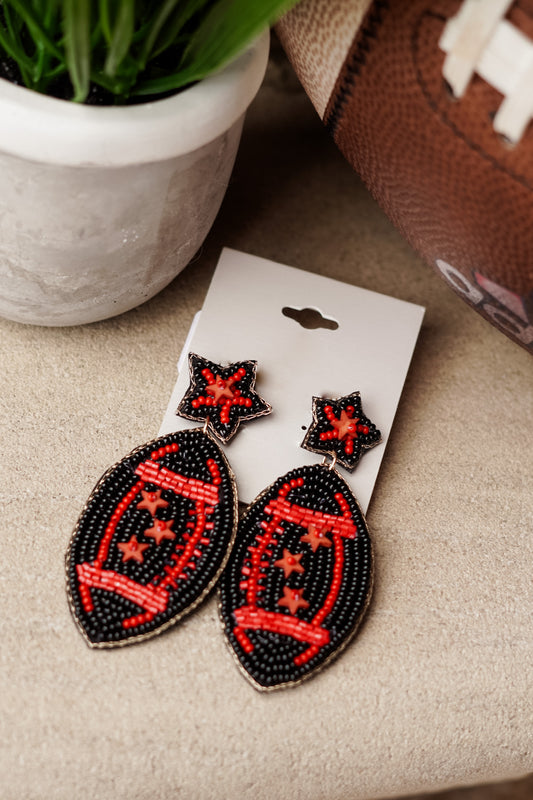 Red and black, Red and Black!! For all the red and black teams out there, these Snap The Ball Beaded Earrings will be your favorite accessory under the Friday or Saturday Night Lights!!  Snap The Ball Beaded Earrings Football and Stars Stud Post Back. Red and black beaded football earrings, black background with red outline and red stars.