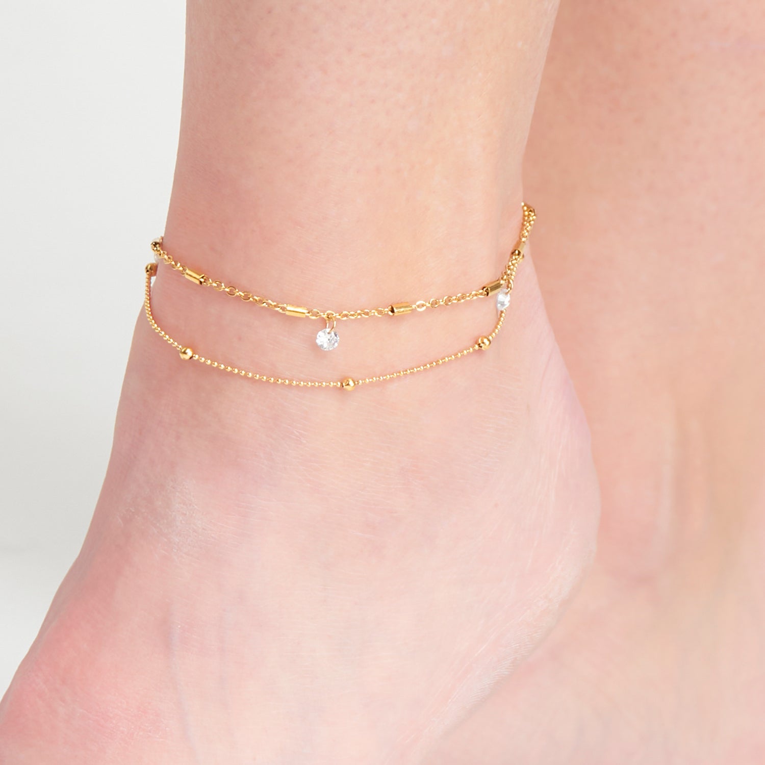 gold anklet with two rows, the top one with crystal pendants, and bottom with gold ball detailing