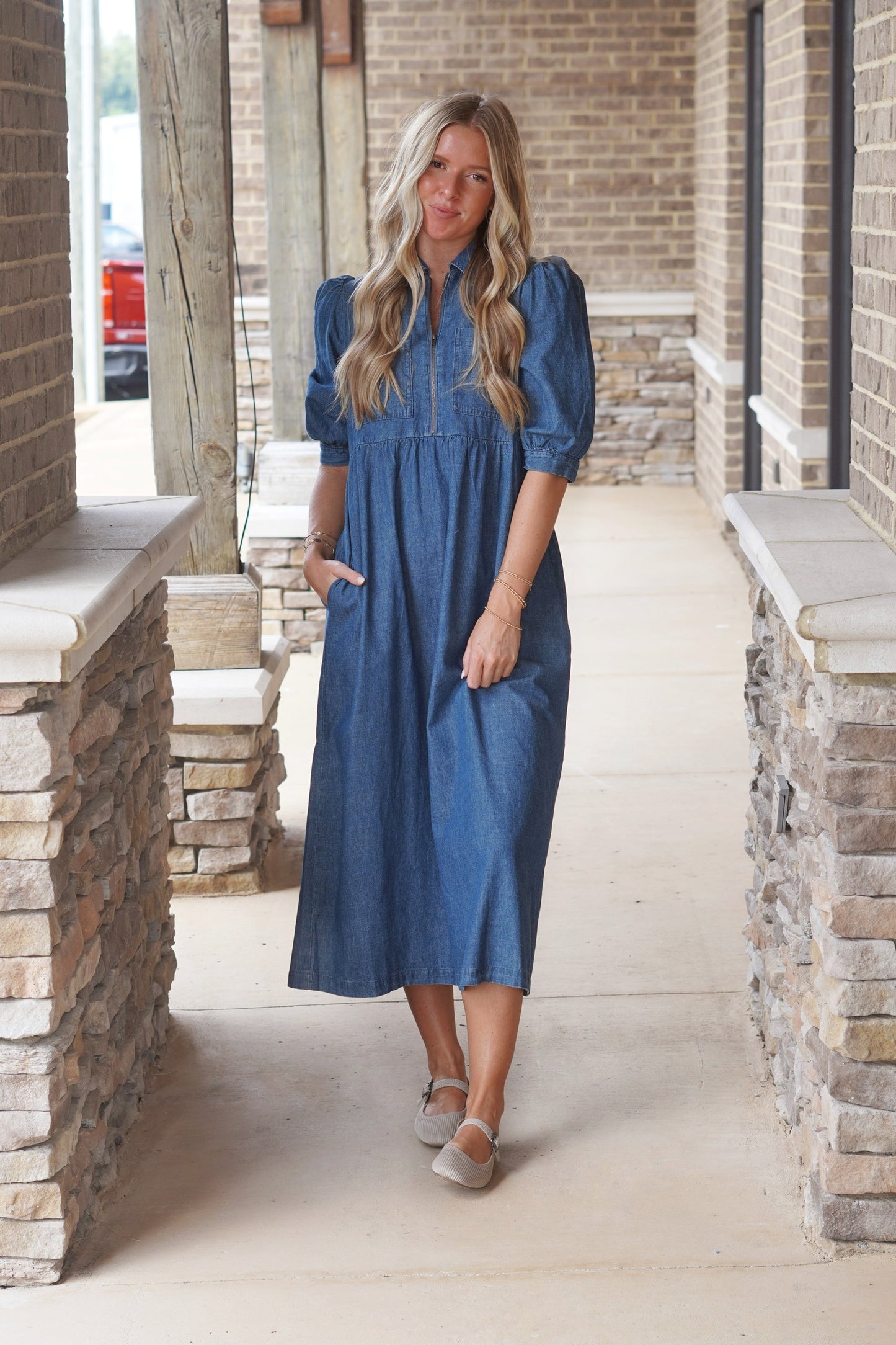 woman wearing a denim maxi dress with puff short sleeves and the top part is collared and zips up