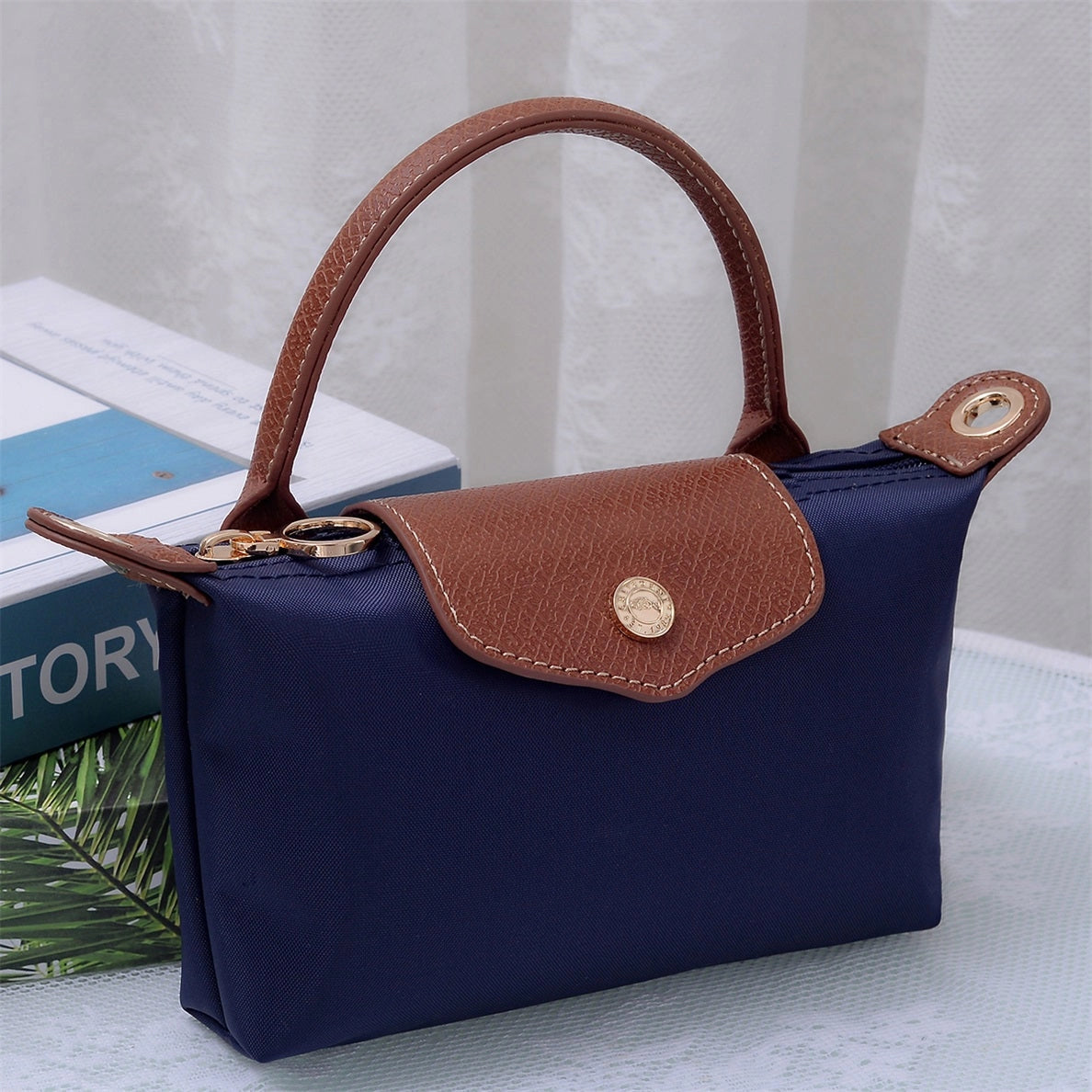 Small navy handbag with brown leather and gold accents 