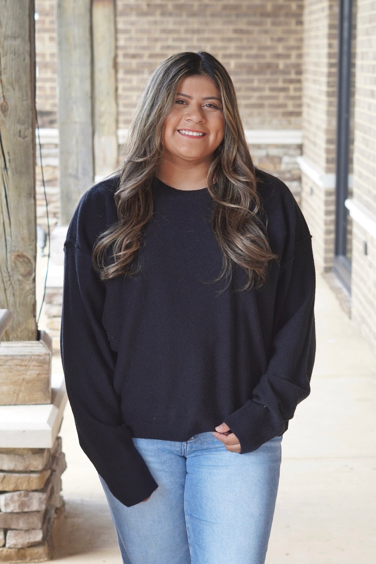 Woman wearing a black colored long sleeve sweater paired with light wash denim jeans 