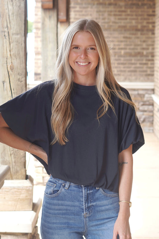 Women wearing a bubble sleeve navy  top, round neckline, and elastic band at the bottom 