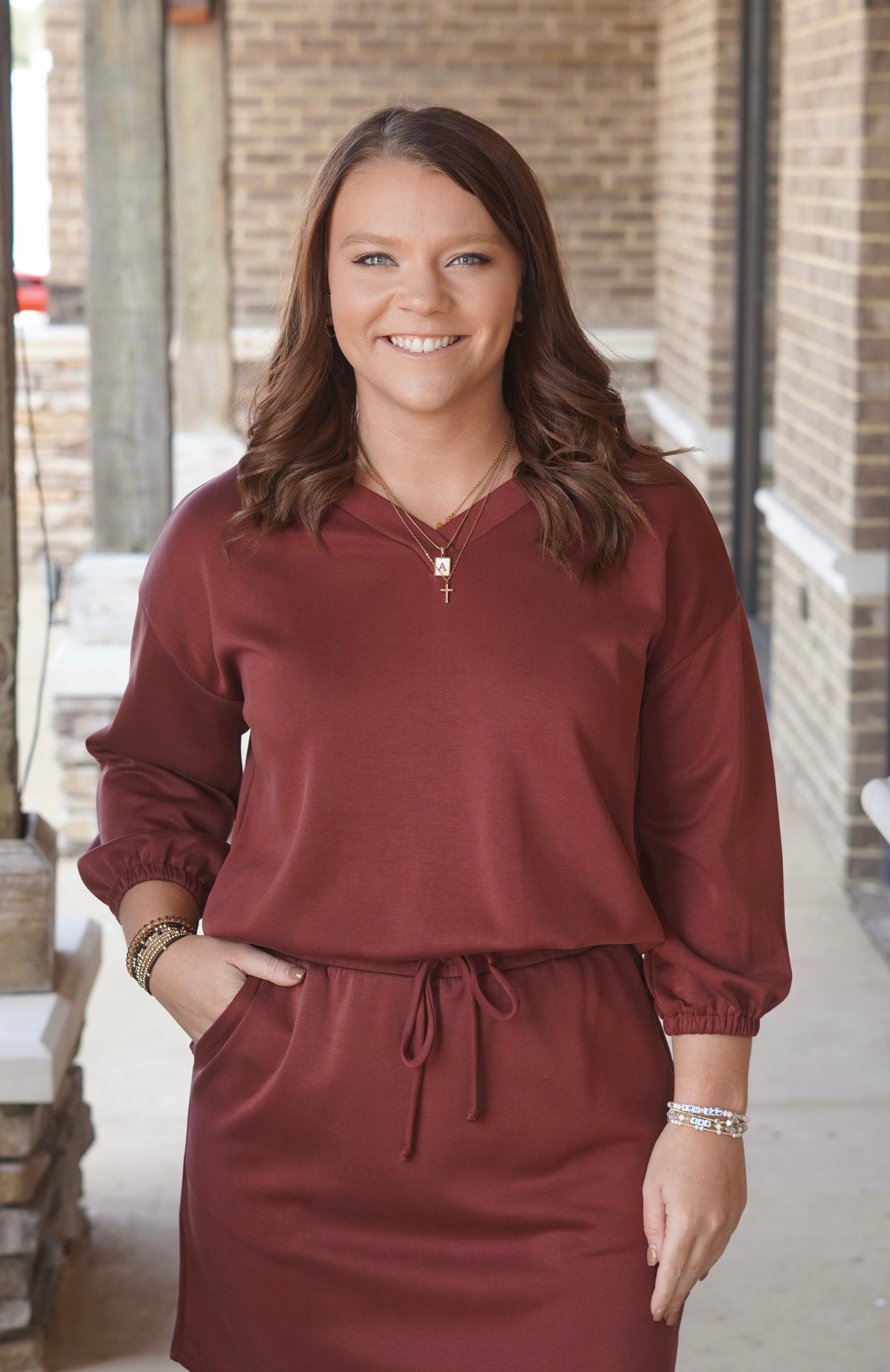 Woman wearing a wine colored v-neck sweatshirt with cinched cuffs paired with a matching skort