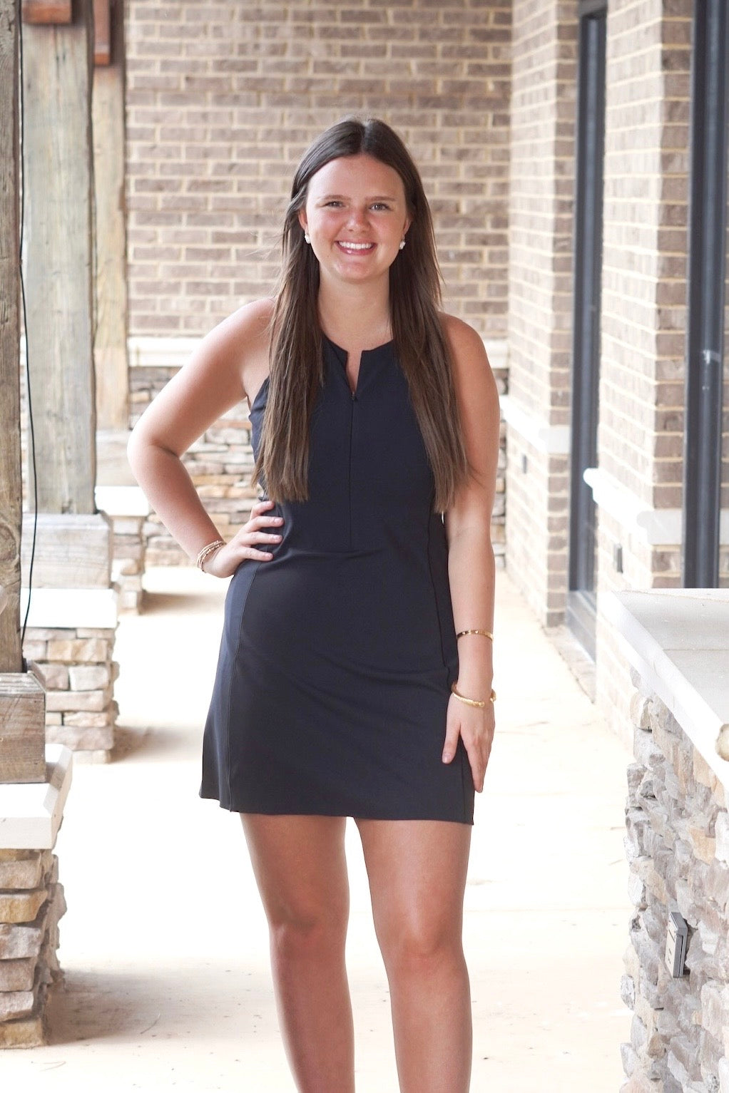 black athletic dress, front zipper, fitted, mid thigh length, sleeveless, round neckline. 